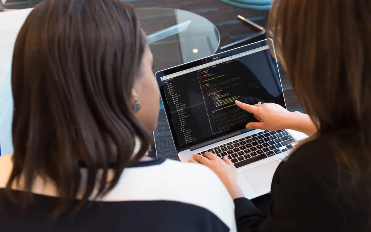 Two colleagues reviewing work together on a laptop